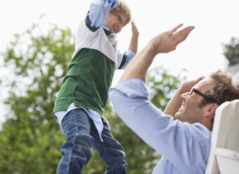 Father and son high fiving outdoors - CAIF01462