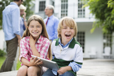 Kinder benutzen gemeinsam ein digitales Tablet im Freien - CAIF01464