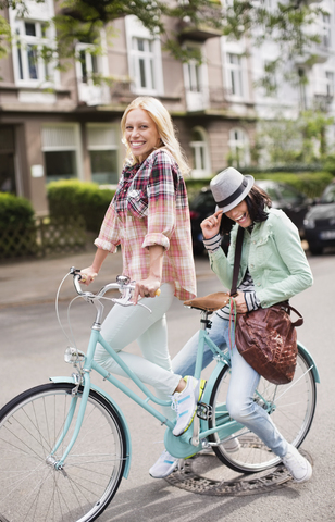 Frauen fahren gemeinsam Fahrrad auf einer Straße in der Stadt, lizenzfreies Stockfoto
