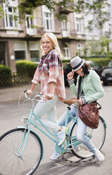 Frauen fahren gemeinsam Fahrrad auf einer Straße in der Stadt - CAIF01519