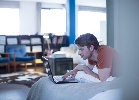 Mann mit Laptop auf dem Bett - CAIF01523