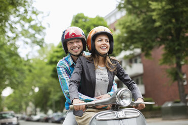 Couple riding scooter together on city street - CAIF01530