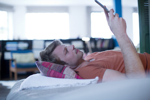 Mann mit digitalem Tablet auf dem Bett - CAIF01535