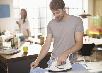 Man ironing shirt in kitchen - CAIF01542