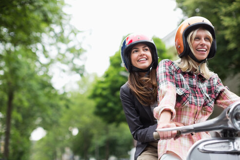 Frauen fahren zusammen im Freien auf einem Motorroller - CAIF01552