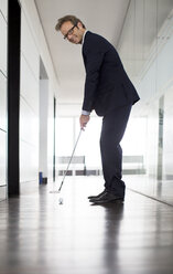 Geschäftsmann legt Golfball ins Büro - CAIF01578