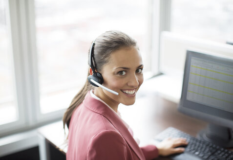 Businesswoman wearing headset at desk - CAIF01602