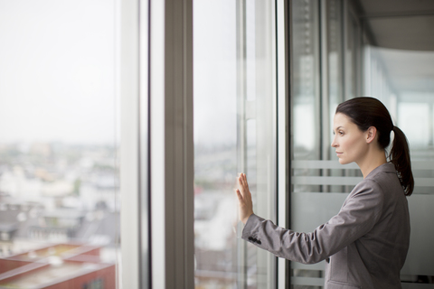 Geschäftsfrau stehend am Bürofenster, lizenzfreies Stockfoto