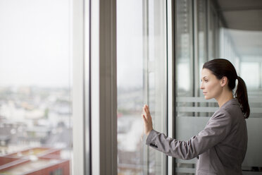 Geschäftsfrau stehend am Bürofenster - CAIF01606