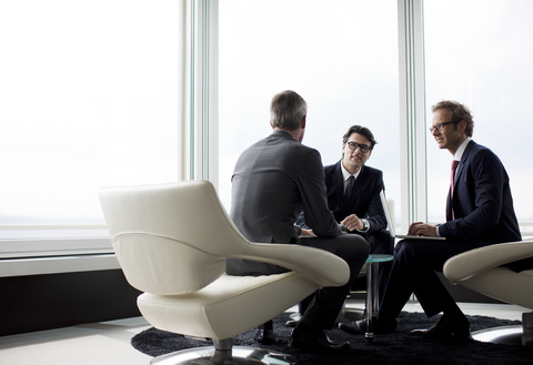 Businessmen talking in office lobby stock photo