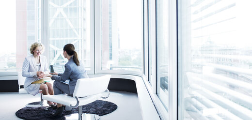 Businesswomen talking in office lobby - CAIF01656