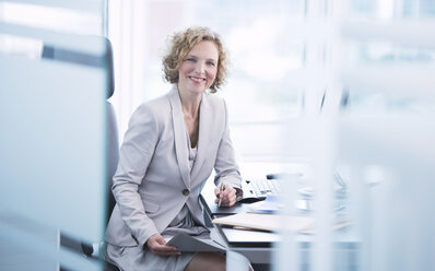 Businesswoman smiling at desk - CAIF01658