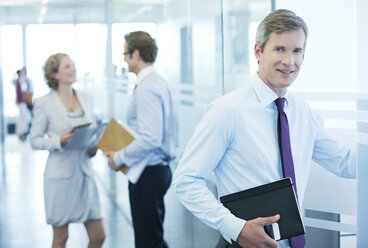 Businessman smiling in office hallway - CAIF01664