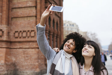 Spanien, Barcelona, zwei glückliche Frauen machen ein Selfie an einem Tor - EBSF02147