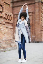 Portrait of exuberant woman standing at brick building - EBSF02173