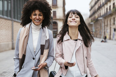 Spain, Barcelona, portrait of two female friends with cell phones in the city - EBSF02189
