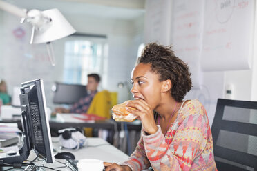 Geschäftsfrau isst Burger am Schreibtisch - CAIF01852