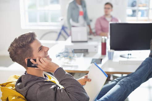 Geschäftsmann, der im Büro mit seinem Handy telefoniert - CAIF01854