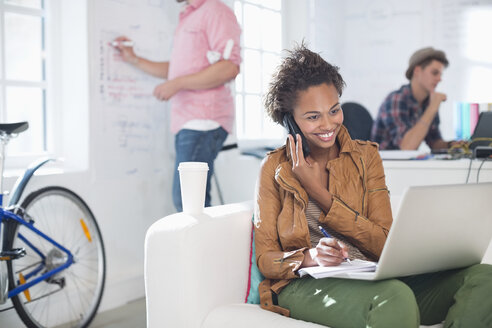 Businesswoman taking notes on phone in office - CAIF01856