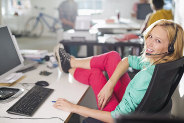 Businesswoman wearing headset at desk - CAIF01865