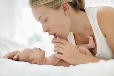Mutter wiegt neugeborenes Kind im Bett - CAIF01877