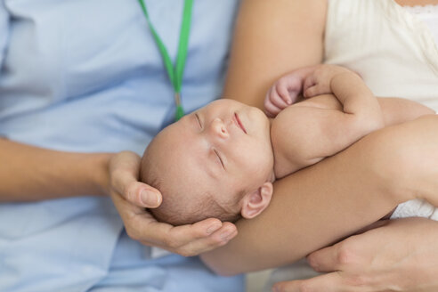 Krankenschwester und Mutter, die ihr neugeborenes Kind wiegen - CAIF01895