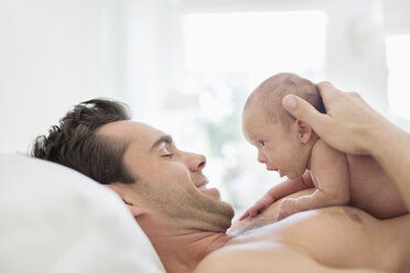 Vater wiegt sein neugeborenes Baby im Bett - CAIF01896