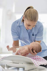 Nurse weighing newborn baby - CAIF01898
