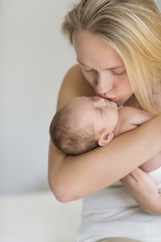 Mutter küsst neugeborenes Baby, lizenzfreies Stockfoto