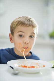 Junge schlürft Spaghetti am Tisch - CAIF01914