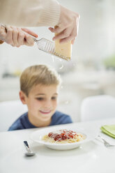 Mutter reibt Käse über die Spaghetti ihres Sohnes - CAIF01921