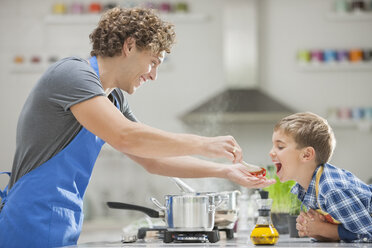 Father and son cooking in kitchen - CAIF01930