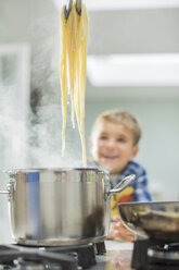 Junge beobachtet Eltern beim Spaghettikochen - CAIF01936