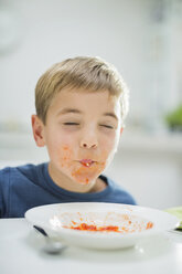 Boy slurping spaghetti at table - CAIF01941