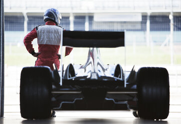 Racer standing with car in garage - CAIF02001