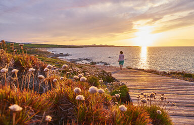 Italy, Sardinia, Lu Litarroni, senior woman on wooden boardwalk at sunset - MRF01890