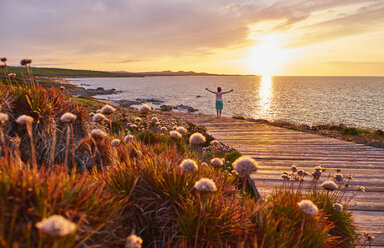 Italy, Sardinia, Lu Litarroni, senior woman on wooden boardwalk at sunset - MRF01891