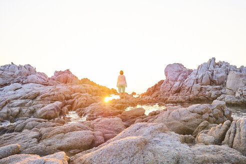 Italien, Sardinien, Rena Majori, Frau steht bei Sonnenuntergang auf einem Felsen - MRF01896