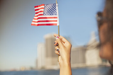 Frau mit neuartigen Nägeln, die die amerikanische Flagge schwenken - CAIF02010