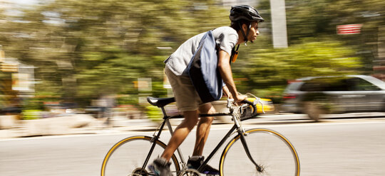 Mann fährt Fahrrad auf einer Stadtstraße - CAIF02032