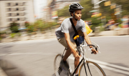 Man riding bicycle on city street - CAIF02034