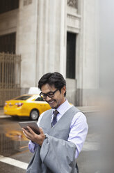 Businessman using tablet computer on city street - CAIF02046