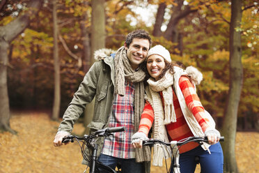 Couple riding bicycles together in park - CAIF02057