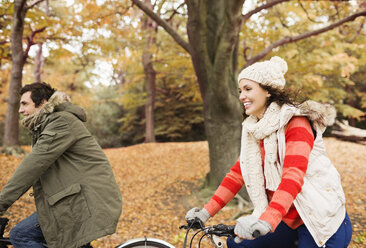 Couple riding bicycles in park - CAIF02061