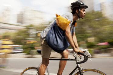 Mann fährt Fahrrad auf einer Stadtstraße - CAIF02098