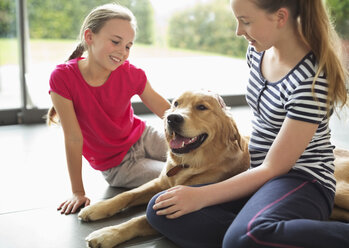 Mädchen entspannen sich mit Hund im Wohnzimmer - CAIF02188