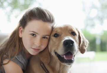 Mädchen umarmt Hund im Haus - CAIF02193