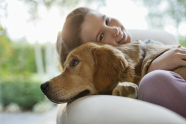 Mädchen entspannt mit Hund auf Sofa - CAIF02201