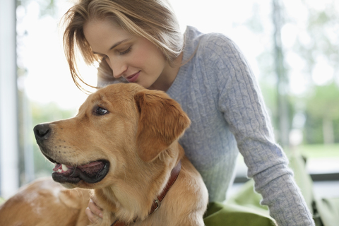 Frau entspannt sich mit Hund in einem Haus, lizenzfreies Stockfoto