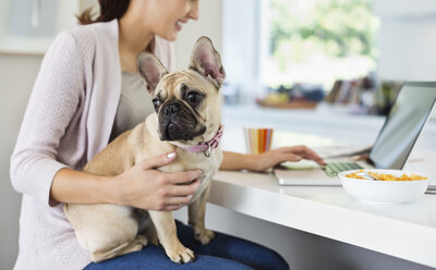 Frau mit Laptop und Hund auf dem Schoß - CAIF02220